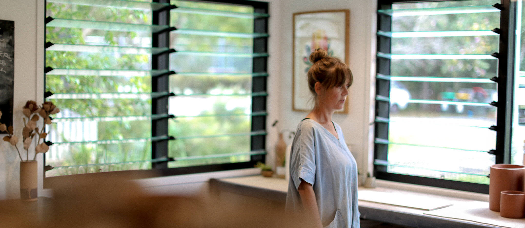 Jenn Johnston wearing a blue chambray dress in her light-filled studio