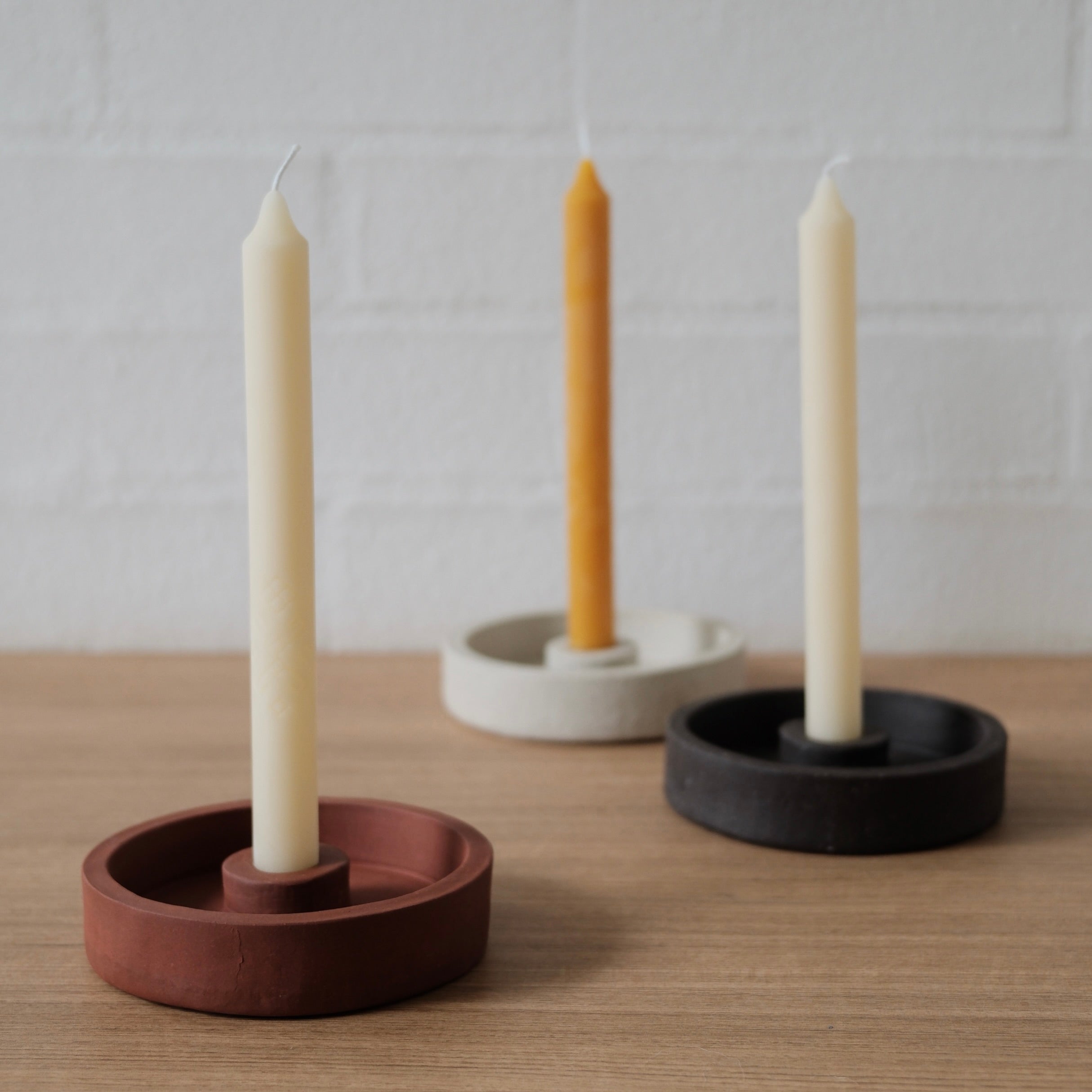 Three candle holders with candles on a wooden surface andwhite background