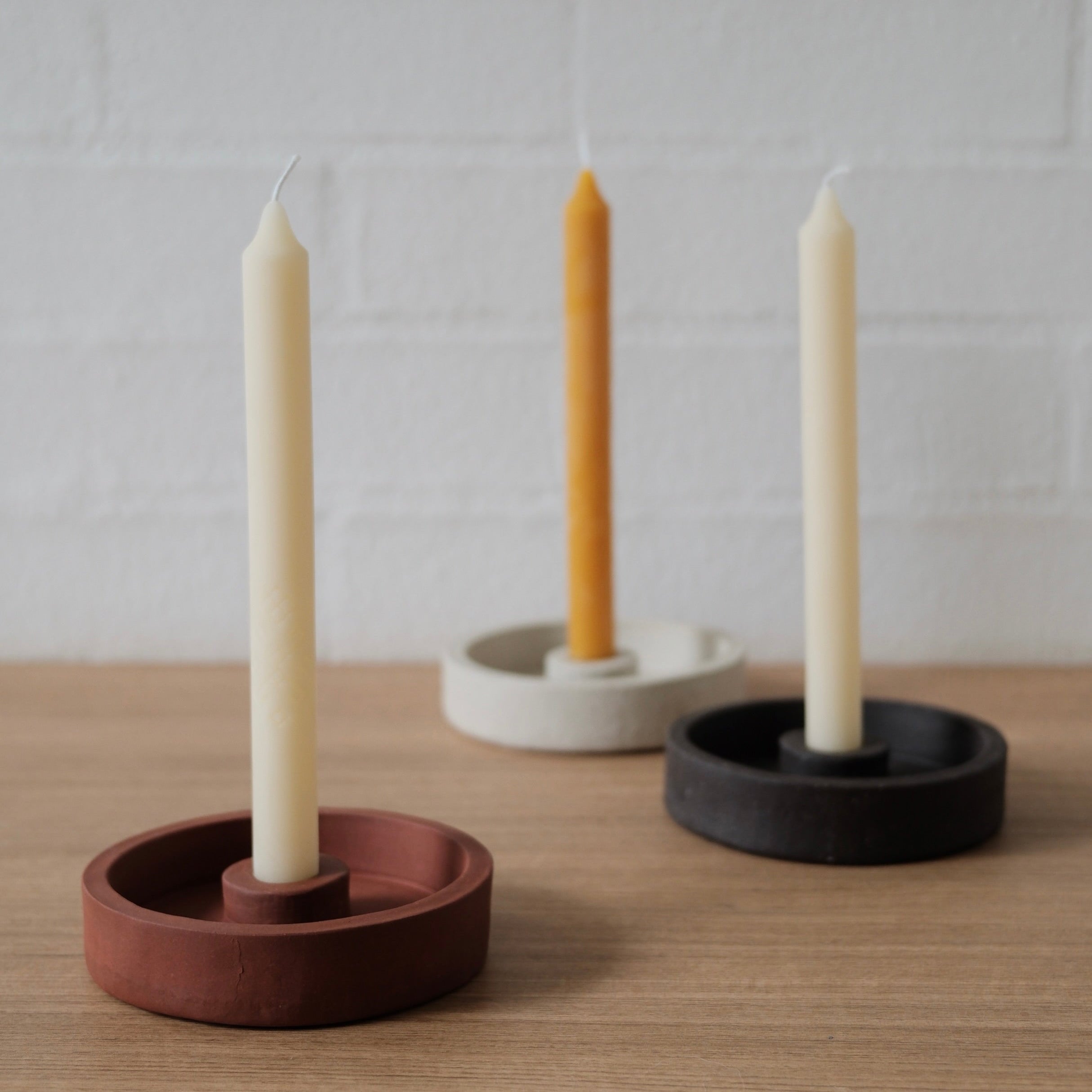 Three candle holders with candles on a wooden surface and white background