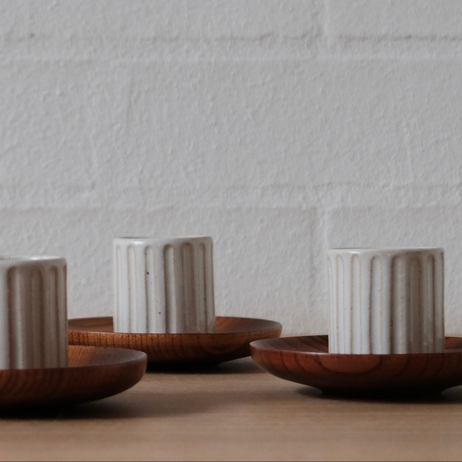 Set of ceramic espresso cups and wooden saucers on a neutral background