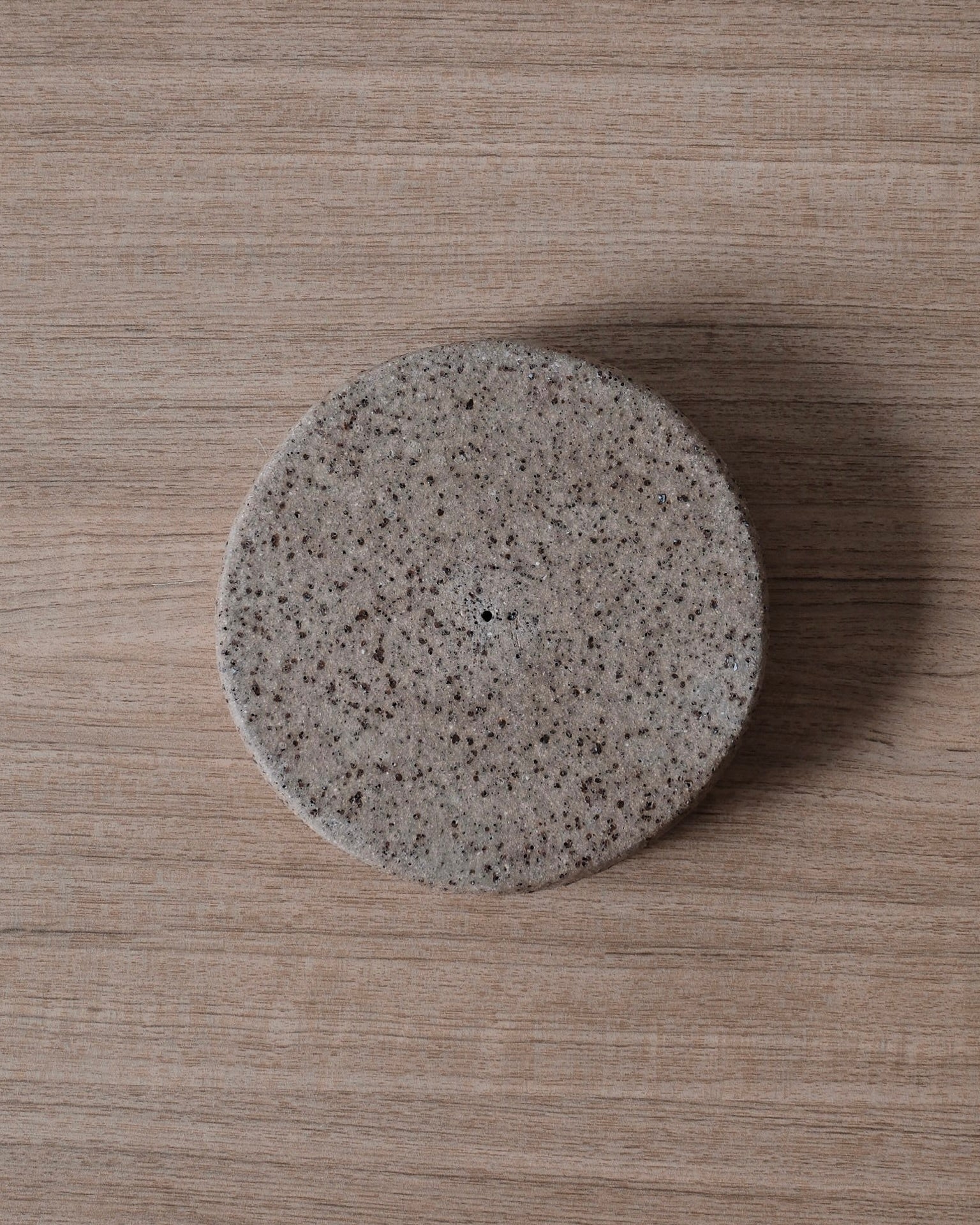 The underside of a round ceramic incense holder on a wooden surface