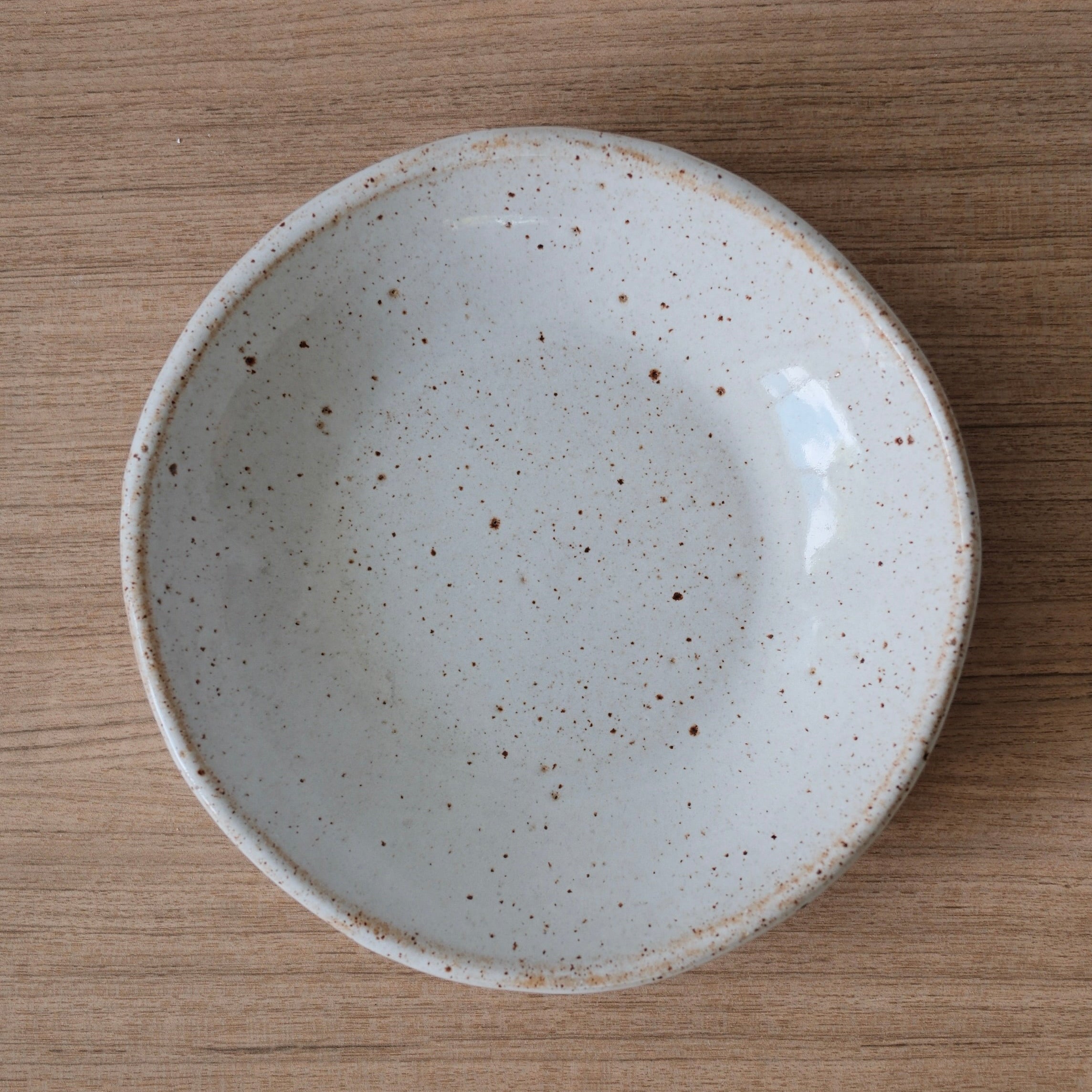 White speckled ceramic bowl on a wooden surface