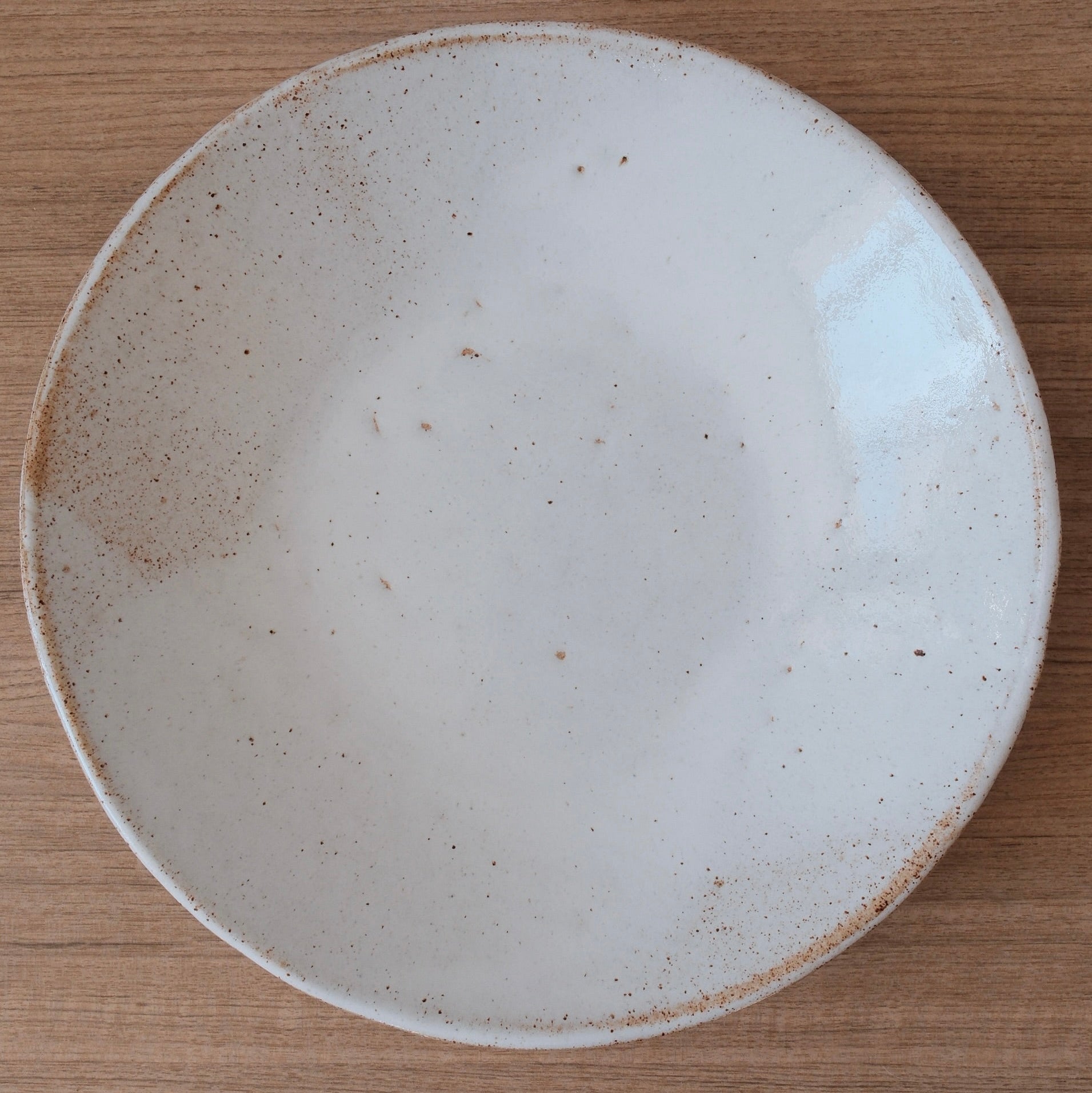 White ceramic platter with speckled texture on a wooden surface