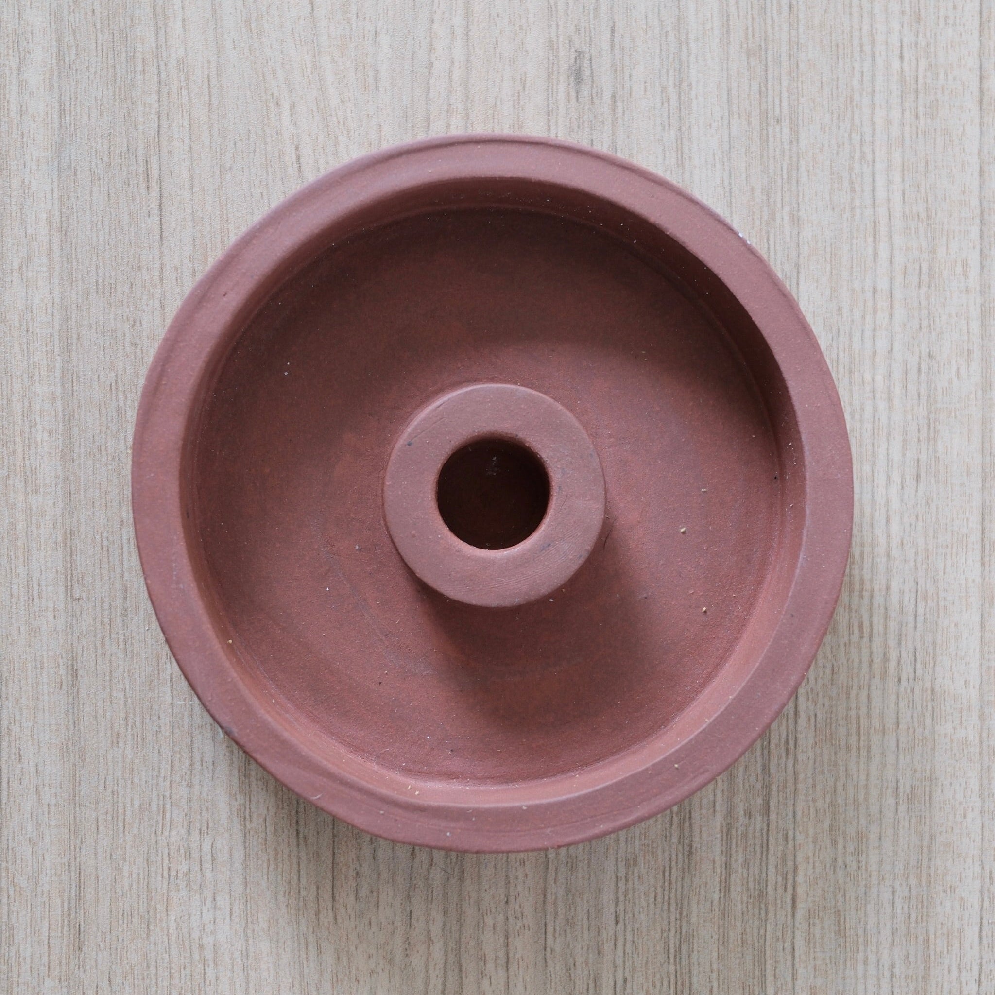 Terracotta candle holder on a light wooden surface
