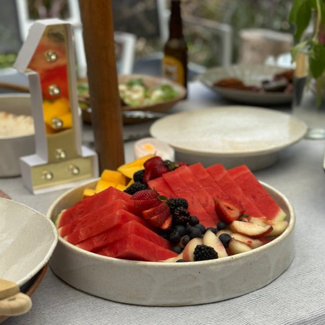 Low serving bowl with sliced fruits on a table with a blurred background