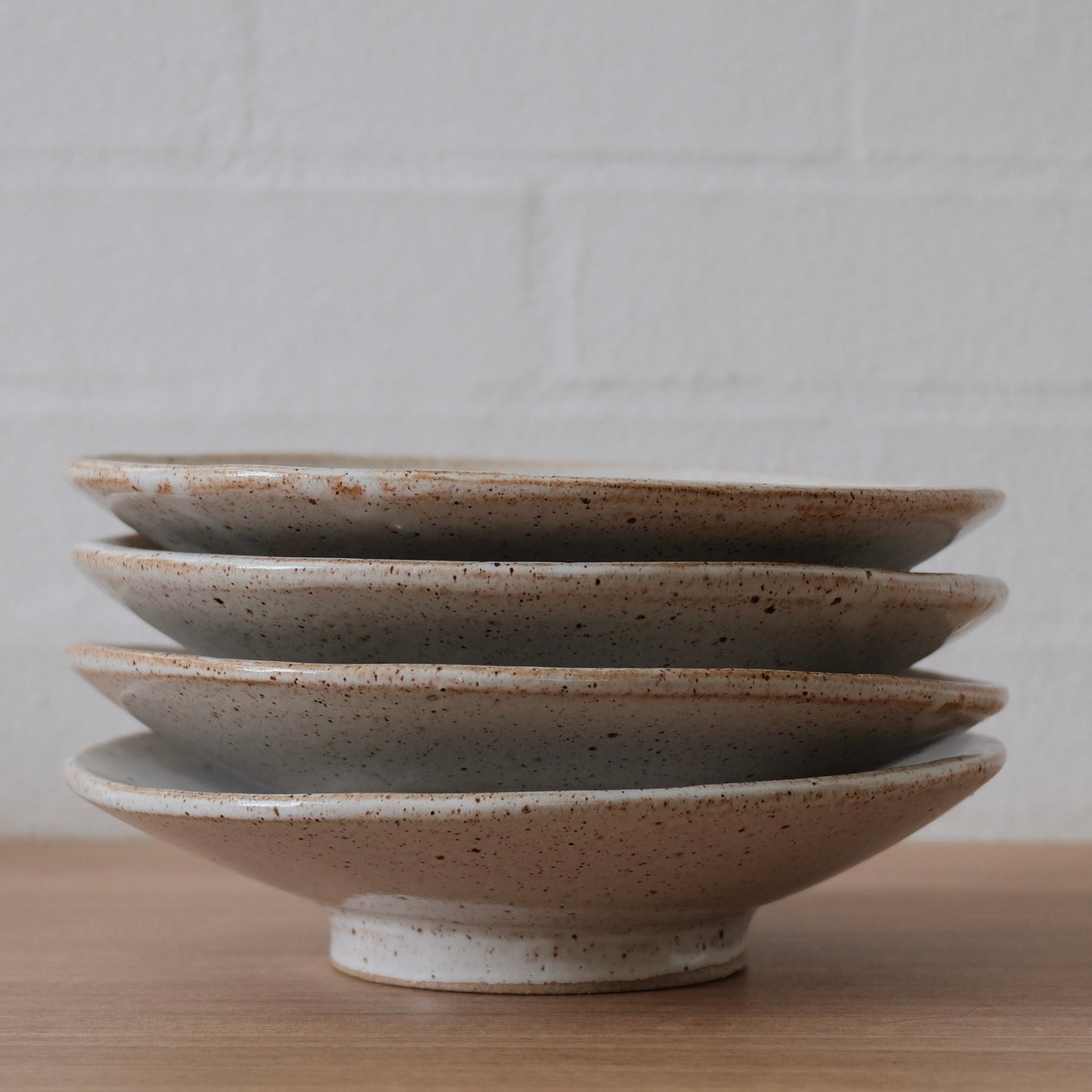 Stack of ceramic bowls on a wooden surface with a neutral background