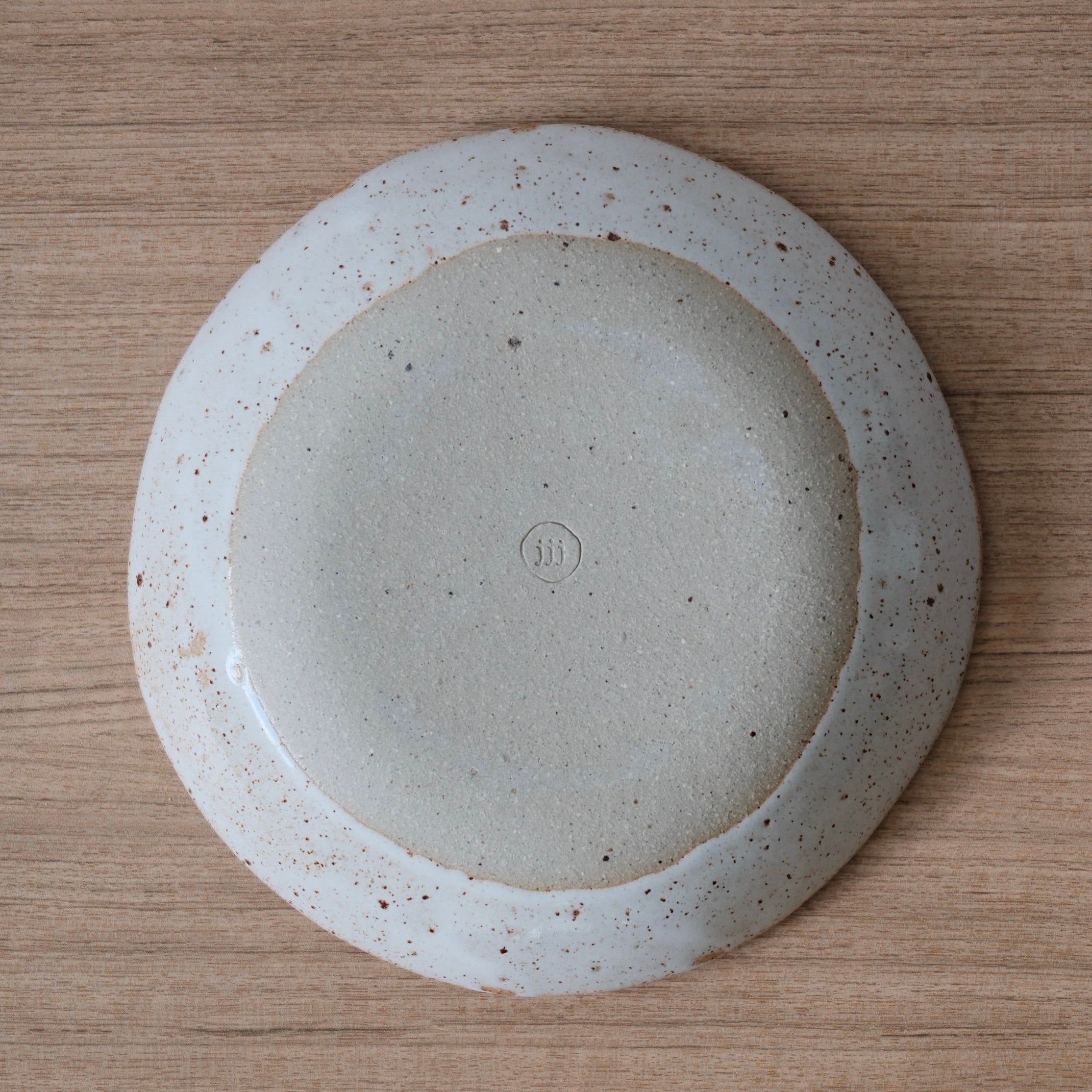 Underside of white ceramic bowl showing unglazed section and maker's stamp