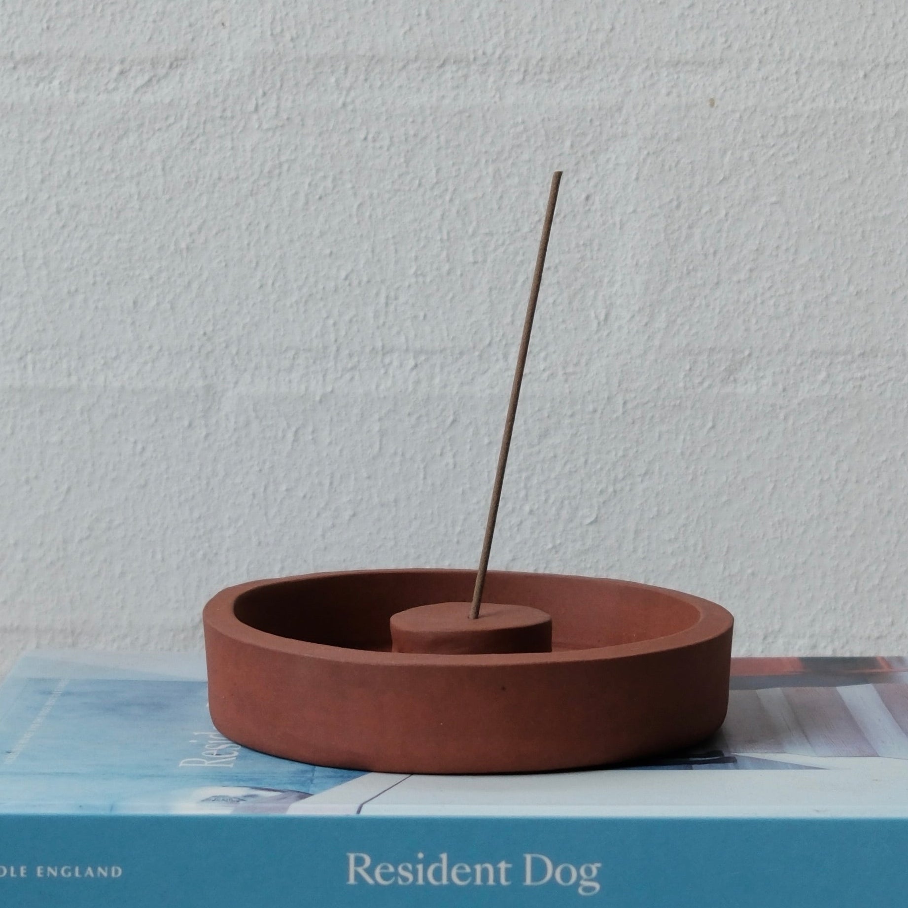 Ceramic incense burner on top of two books with a plain background