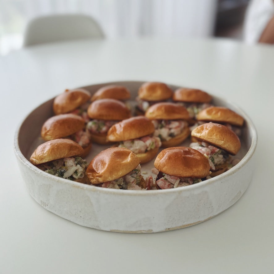 Round ceramic dish with small sliders on a white surface