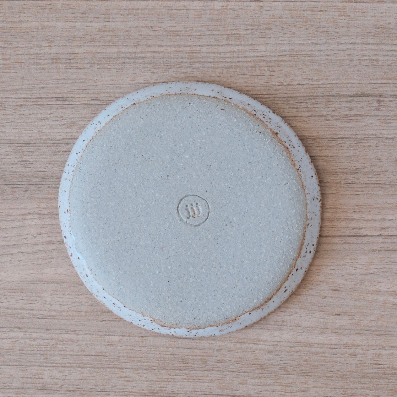 Underside of small white ceramic plate showing makers mark