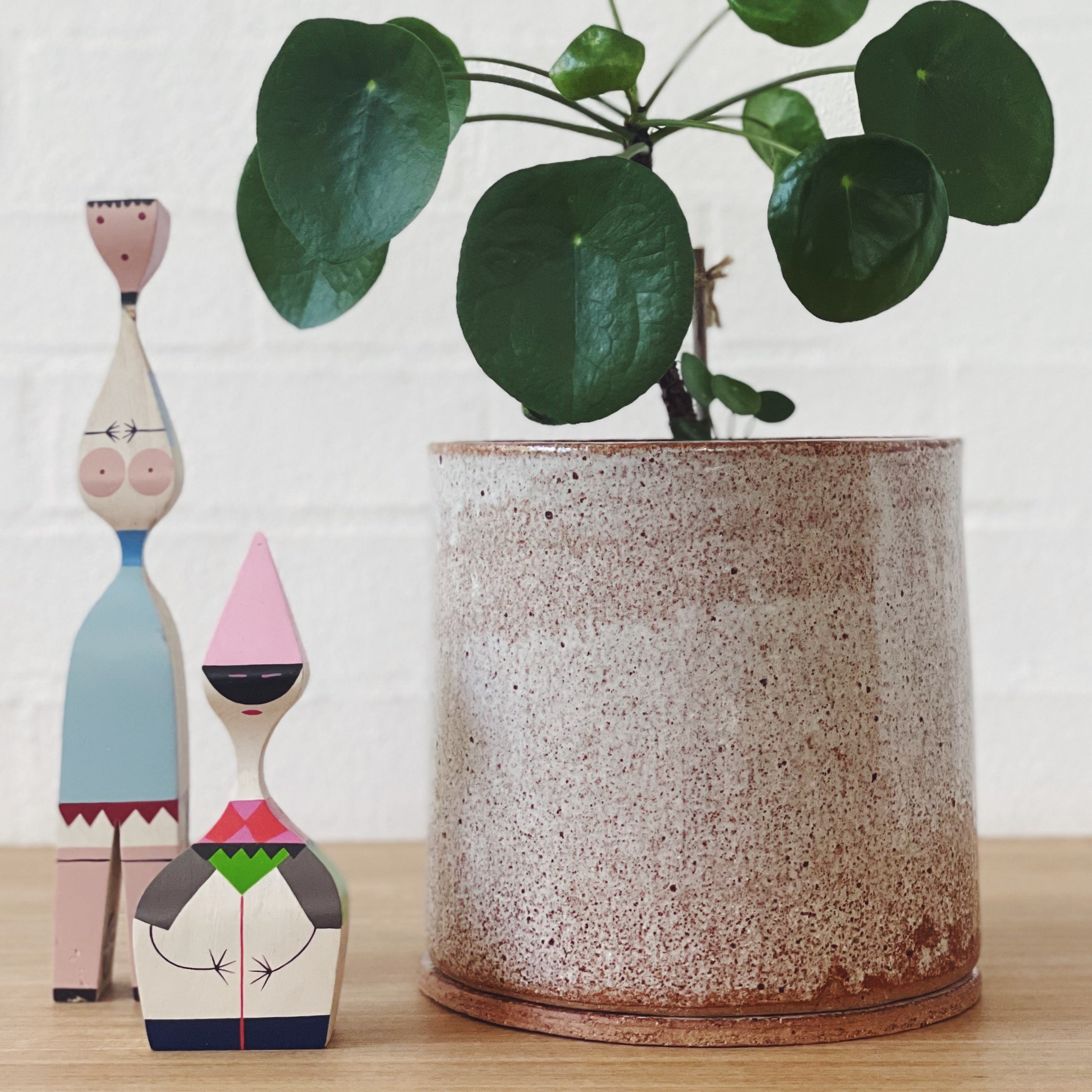 Large golden white ceramic planter with two colourful, wooden dolls